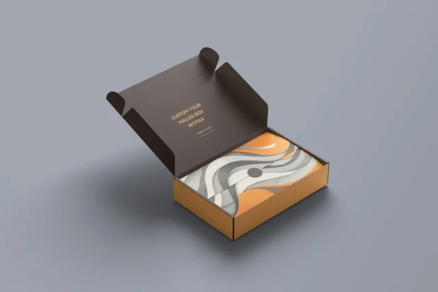 On a grey background, an open Double ClickIt Mailer displays neatly arranged fabric featuring an abstract pattern in orange, black, and white.