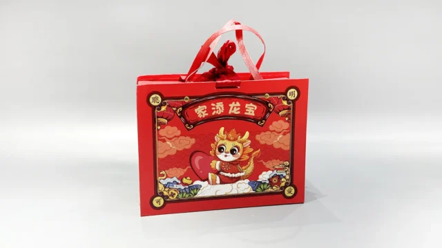 This vibrant red custom packaging box showcases a playful cartoon lion design along with elegant decorative elements. It features sturdy red ribbons tied into bows, providing convenient handles for easy portability and an attractive decorative edge, ideal for presenting gifts stylishly.