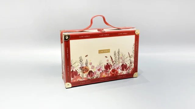 This custom packaging box features a suitcase-style design with a floral motif and red accents, complete with a top handle for easy carrying. Its flip-top style exudes elegance, making it an ideal choice for storing valuables or presenting gifts in a sophisticated manner.