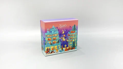 The image showcases a vibrant, customized gift box adorned with lively illustrations of people and animals. It features a unique skincare packaging design, paired with a distinct purple lift-off lid placed nearby.