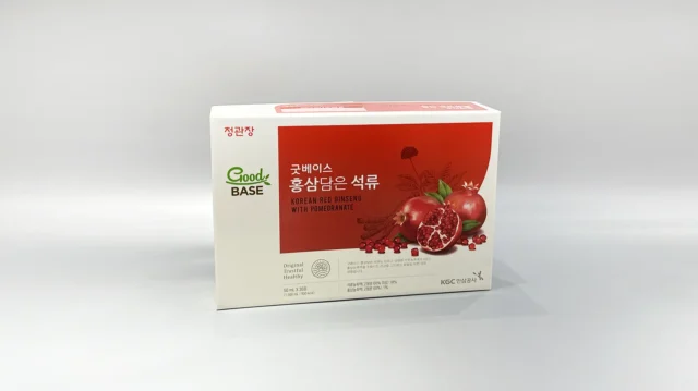 The product is a custom box packaging for a Korean Red Ginseng with Pomegranate product. The box features vibrant and detailed illustrations of ginseng roots and pomegranate fruits, giving it an appealing and eye-catching design. The overall color scheme complements the images, set against a gray surface that enhances the vividness of the artwork. This bespoke packaging highlights both traditional and contemporary aesthetics, reflecting the premium quality of its contents.