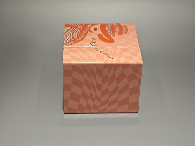 Orange Mecca box featuring a stylized face illustration