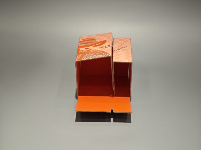 Orange Mecca box featuring a stylized face illustration