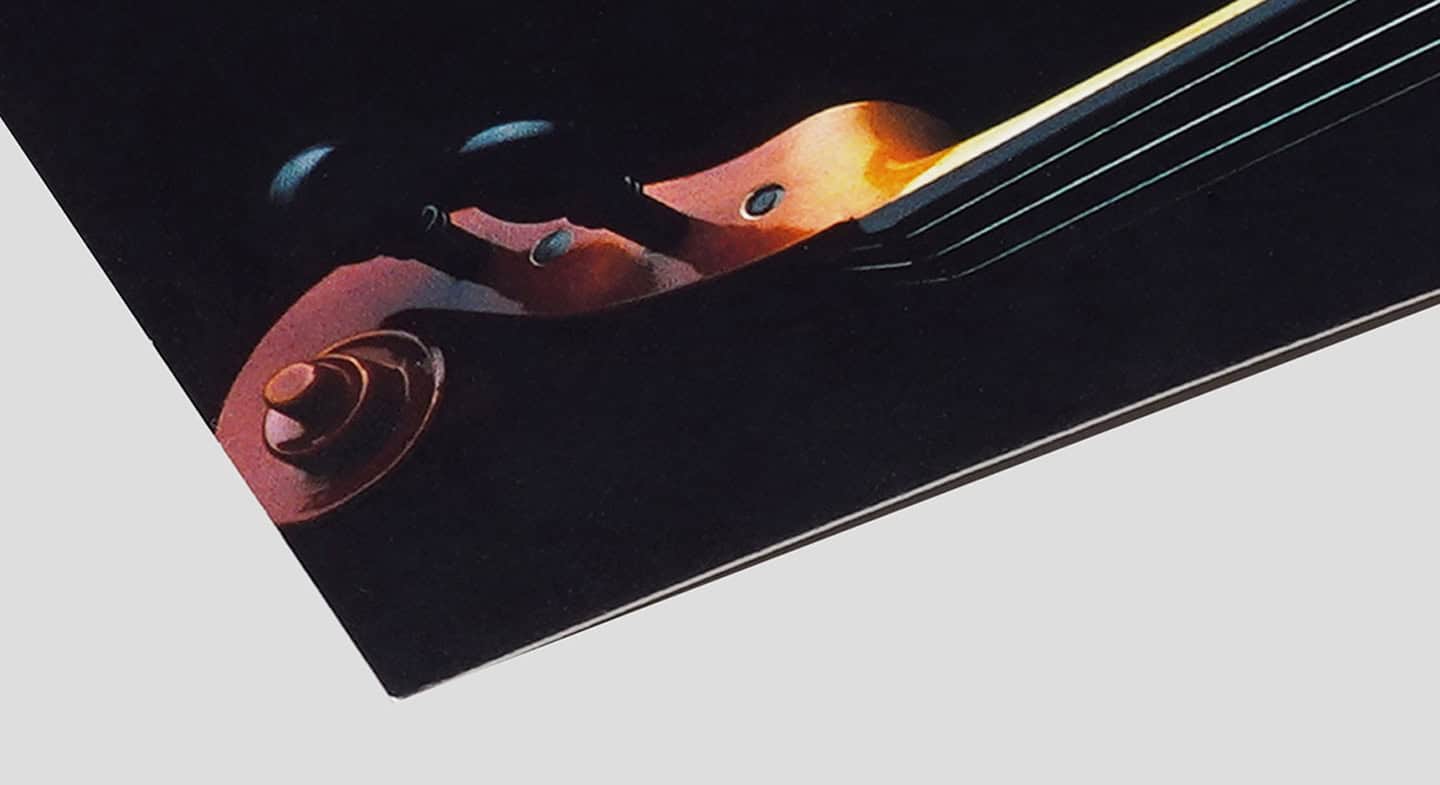 A close-up of a spot gloss varnish applied to a poster, showcasing the glossy finish on the violin's body, with a black background and a white edge.