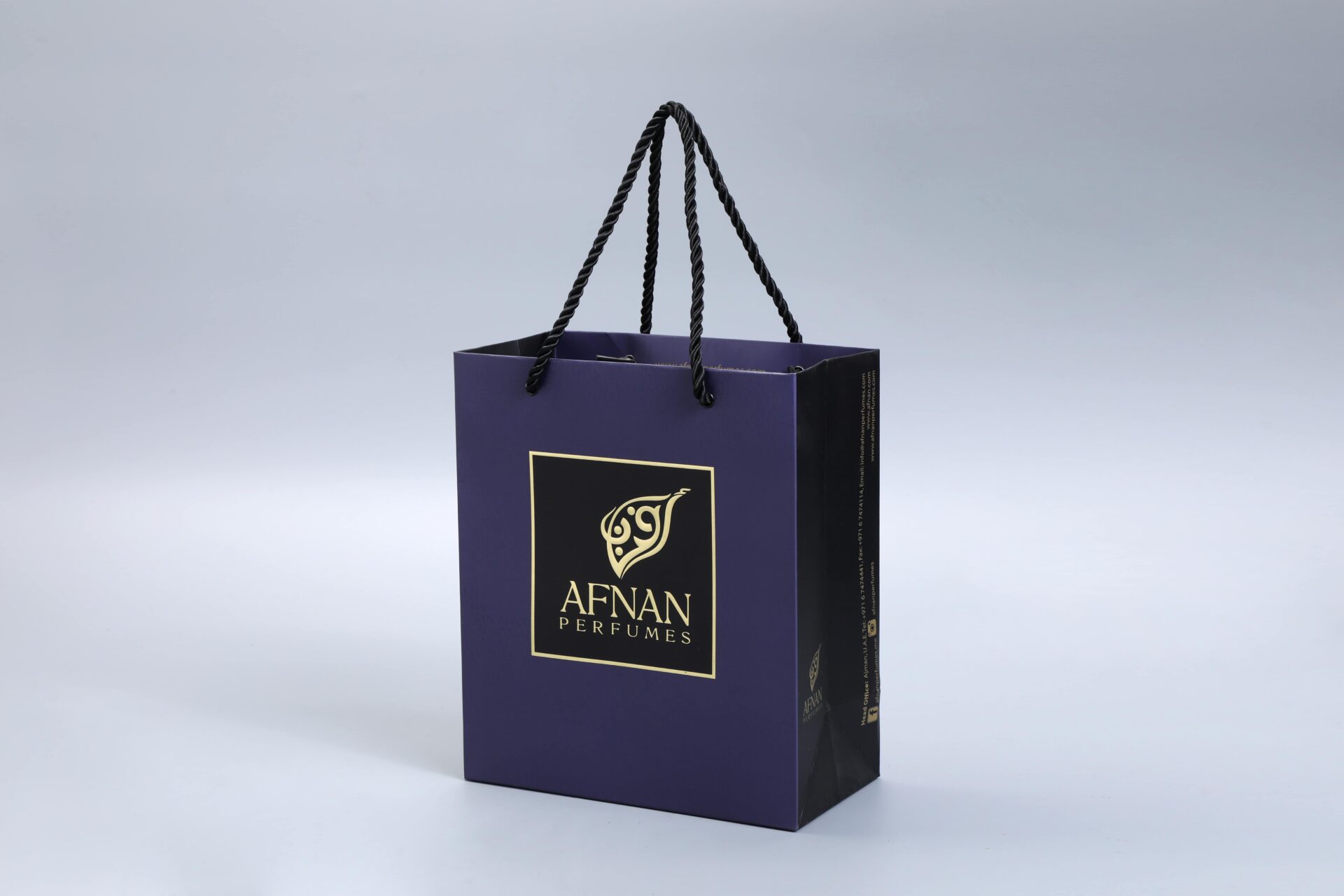 A custom-designed dark blue gift box with sturdy black rope handles and an elegant gold logo, showcased on a light gray background.