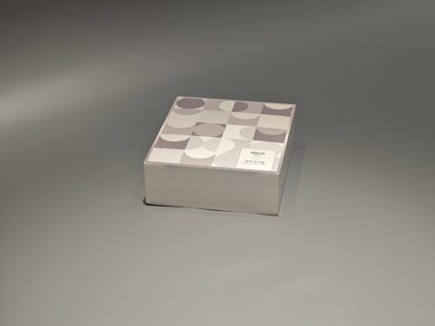 A custom packaging box with a lift-off lid, showcasing an intricate pattern, is displayed elegantly