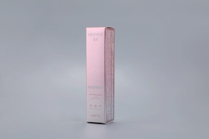 A custom pink and white box designed for "Heuyea Soothing Essence" set against a gray background.