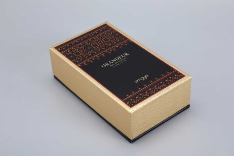 A gold gift box with a black lid, showcasing elegant red geometric patterns.