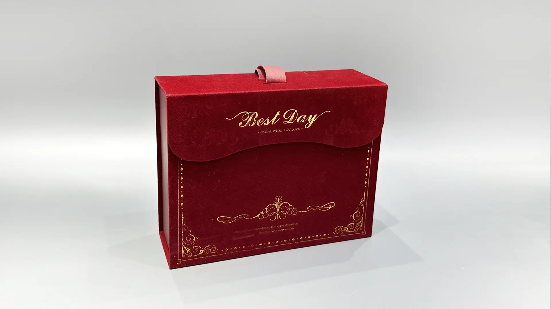 A luxury gift box crafted in red velvet with elegant gold embellishments, featuring ornate decorative patterns and a convenient top handle. This custom flip-top design adds an extra touch of elegance to any special occasion.