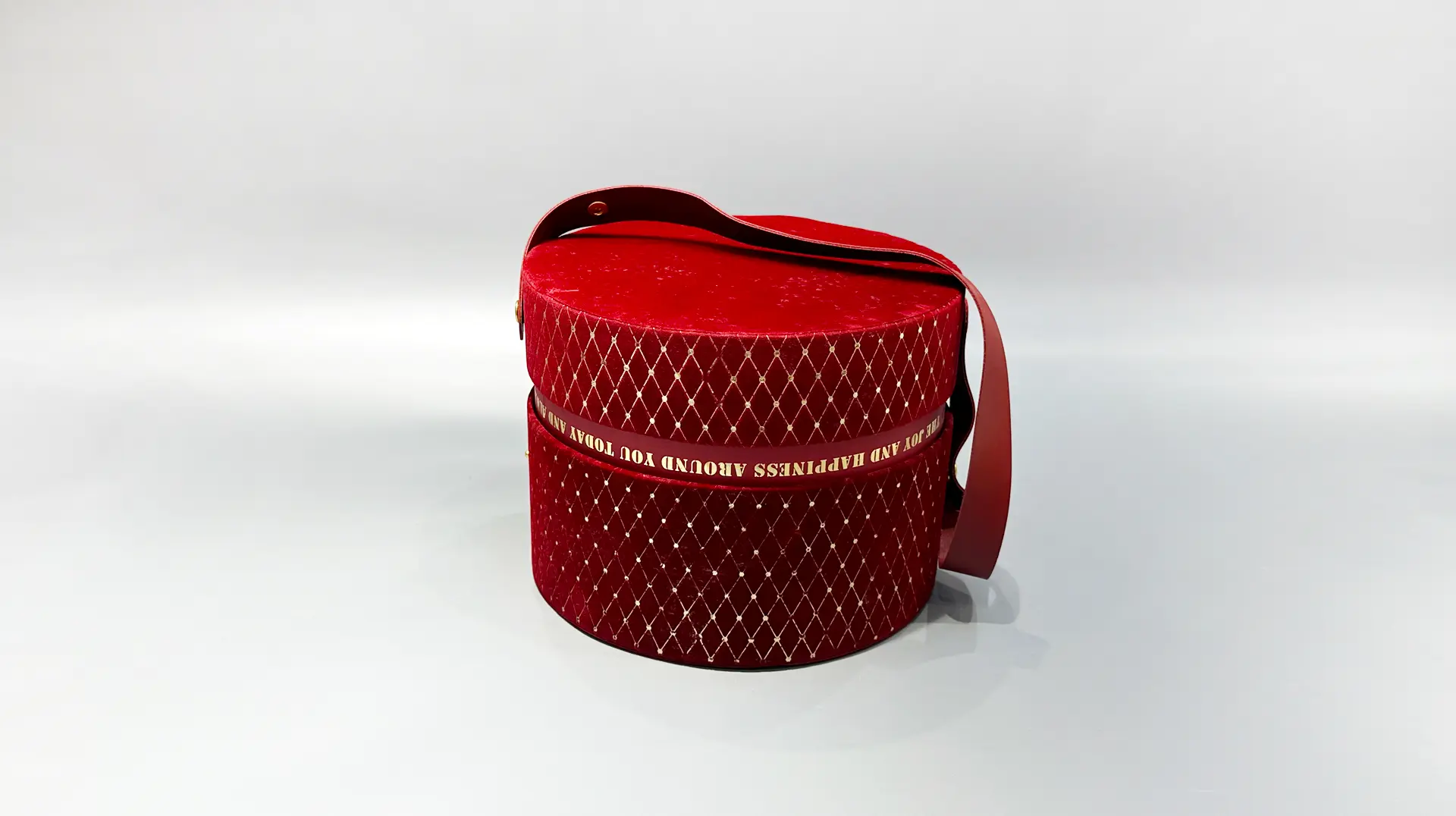 A red cylindrical packaging box featuring a diamond pattern and a black handle, evoking a sense of luxury and elegance, set against a neutral background.