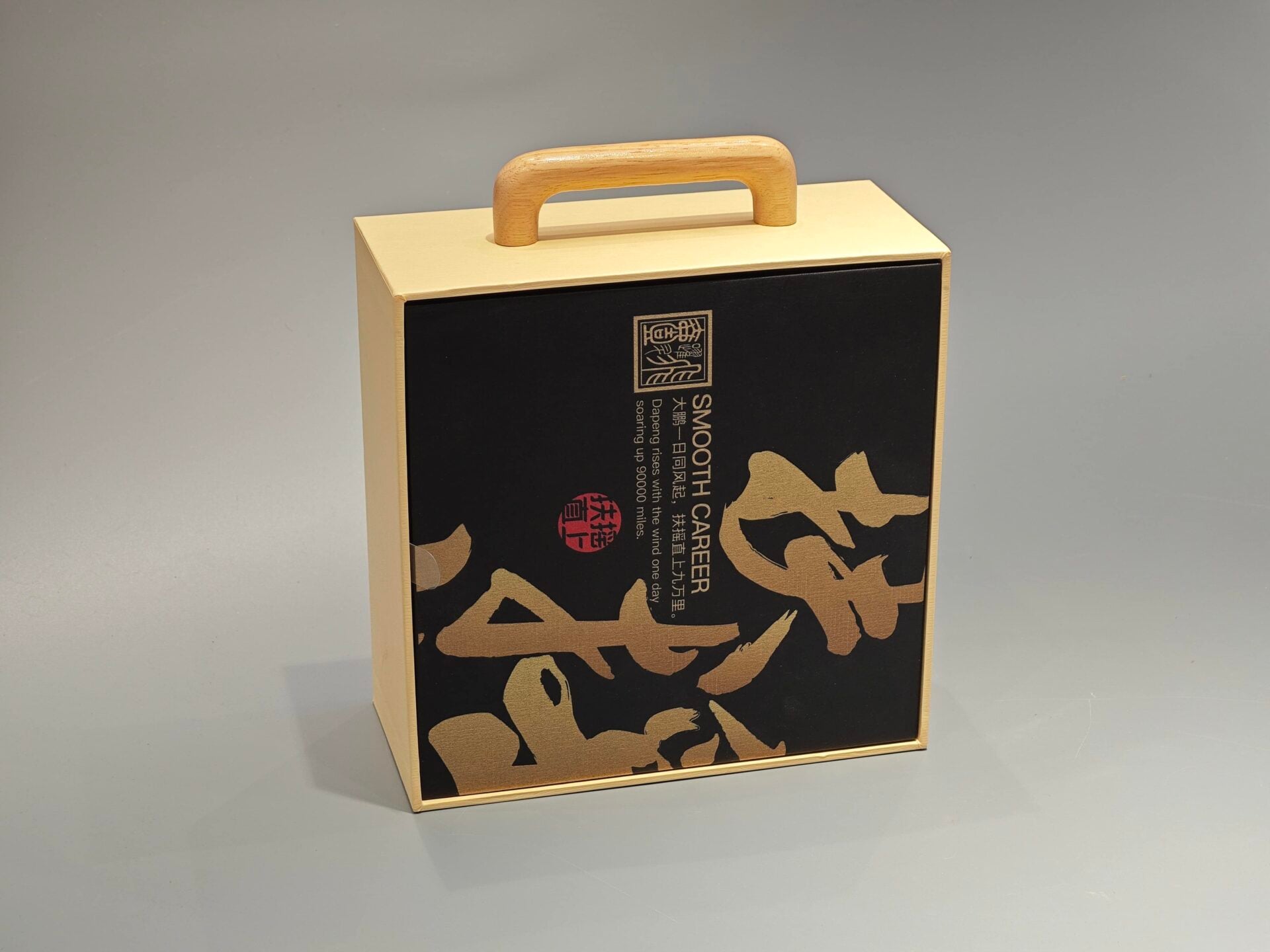 A packaging box with a handle, adorned with black Asian calligraphy and an intricate patterned design.