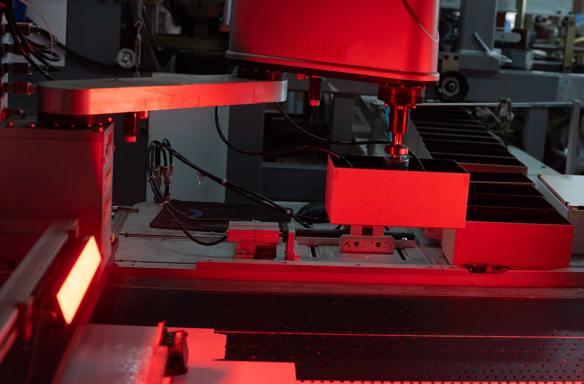 Automated machine part with red lighting in an industrial setting.