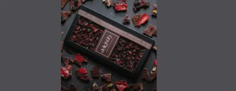 Box of dark chocolate with berries in elegant chocolate packaging and dried strawberries.