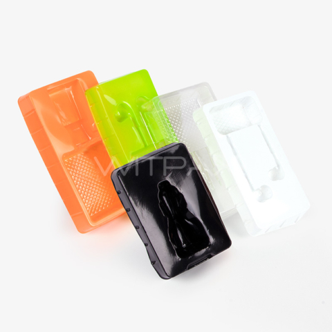Multiple colored thermoformed plastic box inserts in orange, lime green, clear, and black with molded compartments