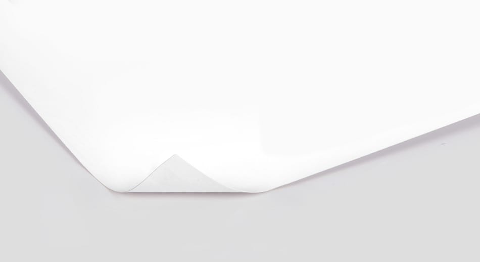 Curled edge of a white board paper on a smooth surface.