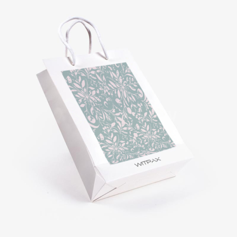 Angled view of custom white paper shopping bag with sage green floral pattern panel and rope handles