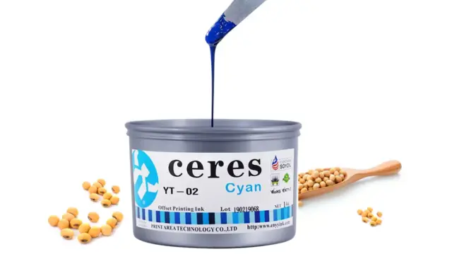 Cyan printing ink being poured from a spatula into a tin, with soybeans nearby.