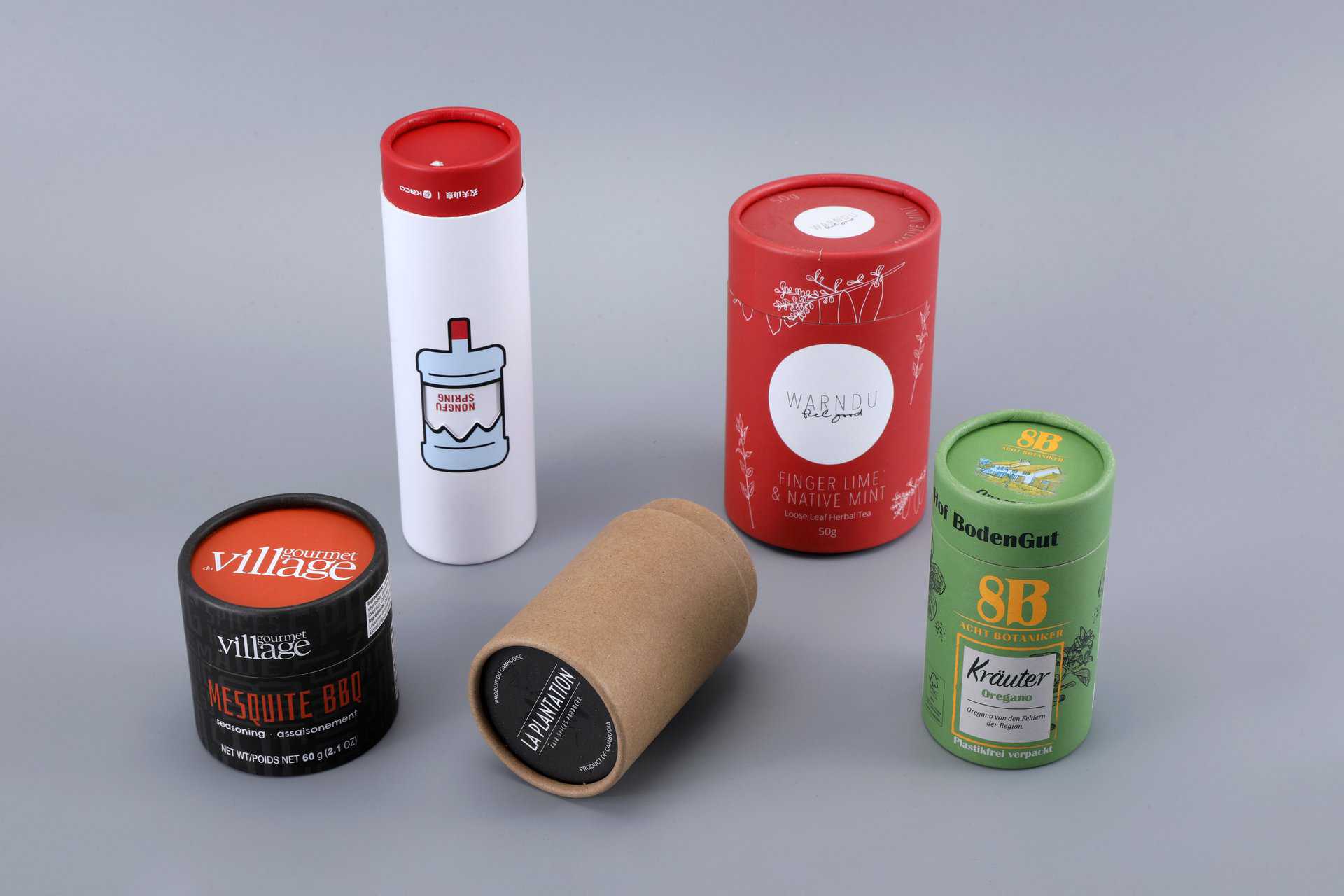 Five cylindrical packaging boxes are arranged on a gray surface.