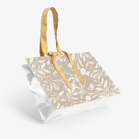 Custom paper shopping bag with floral pattern shown at an angle displaying the structured base and gold ribbon handles