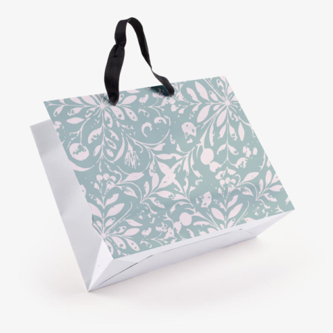 Custom paper shopping bag with sage green floral pattern and black ribbon handle shown at an angle