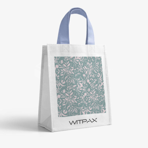 Front view of white non-woven shopping bag with decorative green floral pattern panel and blue fabric handles