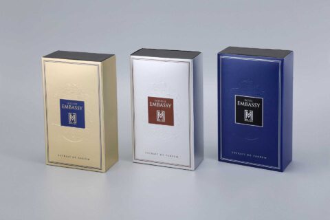 three custom-designed perfume boxes positioned side by side, each showcasing a distinct finish: metallic gold, sleek silver, and vibrant blue.
