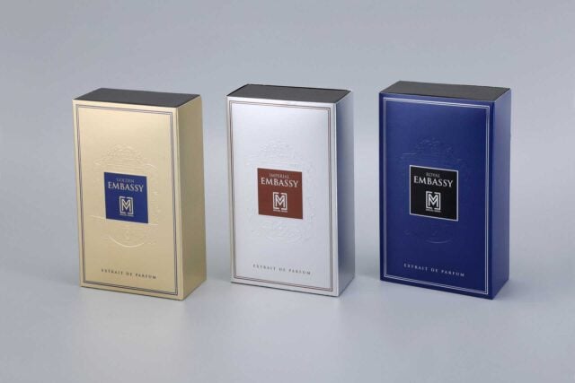 three custom-designed perfume boxes positioned side by side, each showcasing a distinct finish: metallic gold, sleek silver, and vibrant blue.
