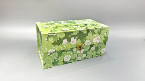 The image showcases a rectangular gift box with a green floral pattern and a gold clasp. It features a practical flip-top design and is set against a plain gray background.