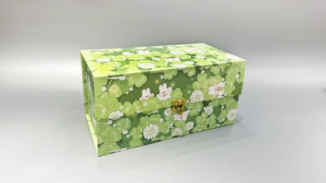 The image showcases a rectangular gift box with a green floral pattern and a gold clasp. It features a practical flip-top design and is set against a plain gray background.
