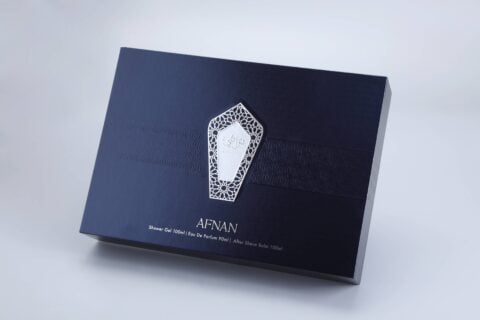 The product is a navy blue box with an elaborate white geometric pattern, showcasing the brand identity "Afnan." It contains shower gel, eau de parfum, and after shave balm.