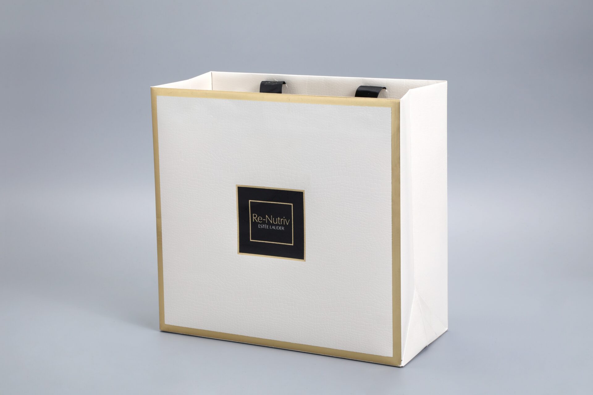This image depicts a white Estee Lauder Re-Nutriv packaging box featuring elegant gold accents and a sleek design, highlighted against a neutral gray background.