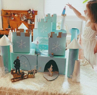 This image showcases our custom box packaging designed as a whimsical cardboard castle, adorned with intricate snowflake patterns and accompanied by toy figures and animals on display.