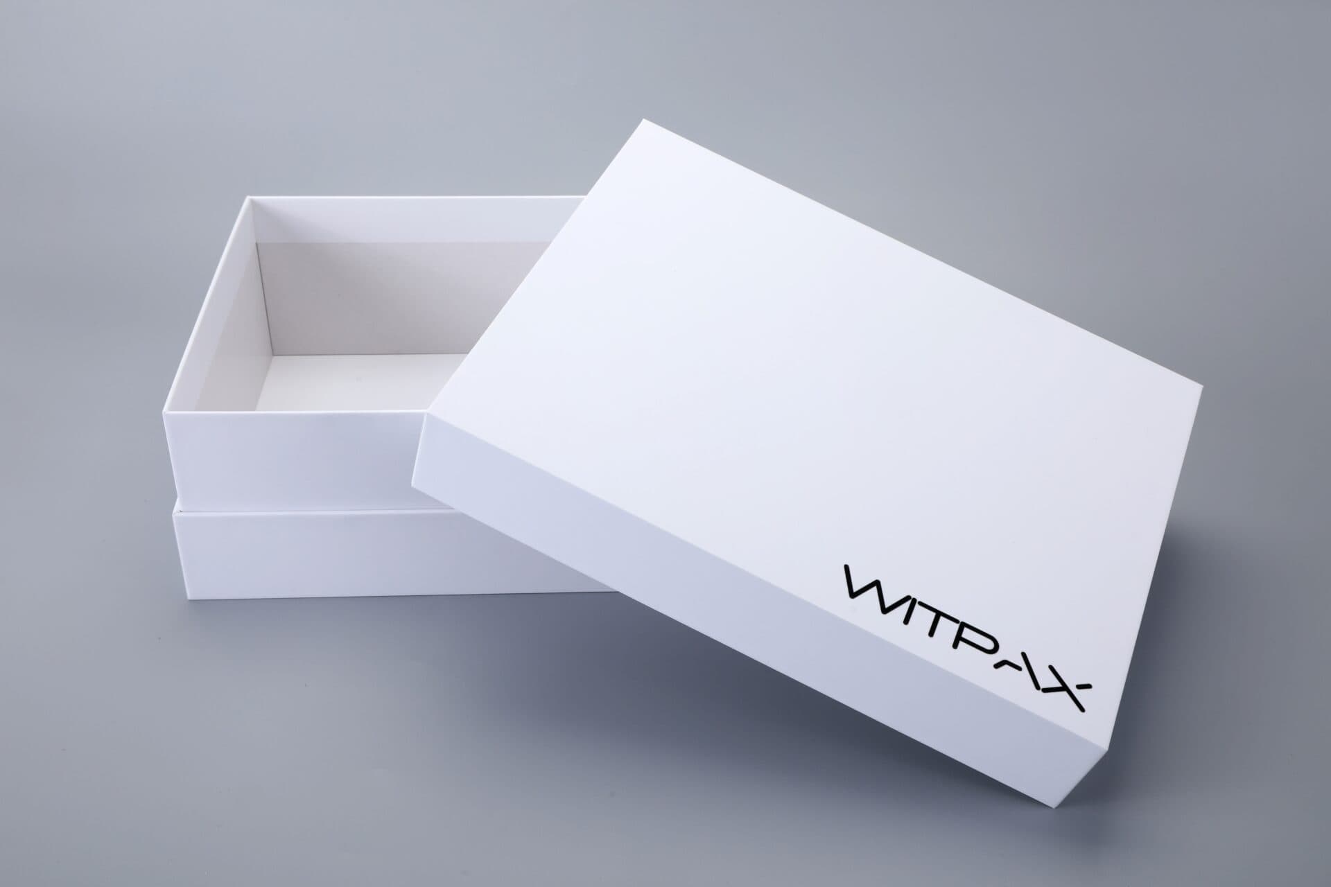 White rigid box with the lid partially open on a grey background.