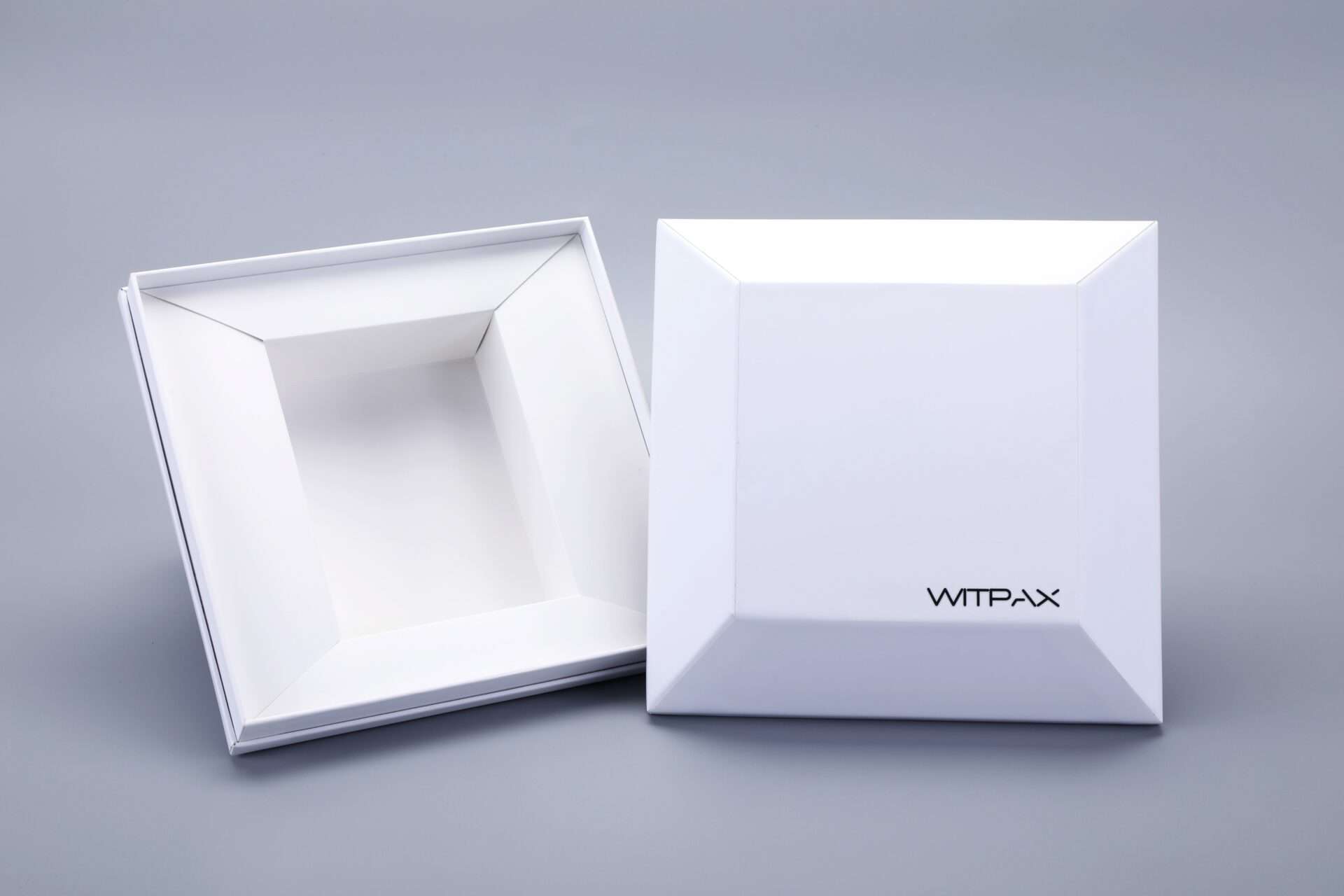 White shaped rigid boxes, one closed and one open, on a gray background.