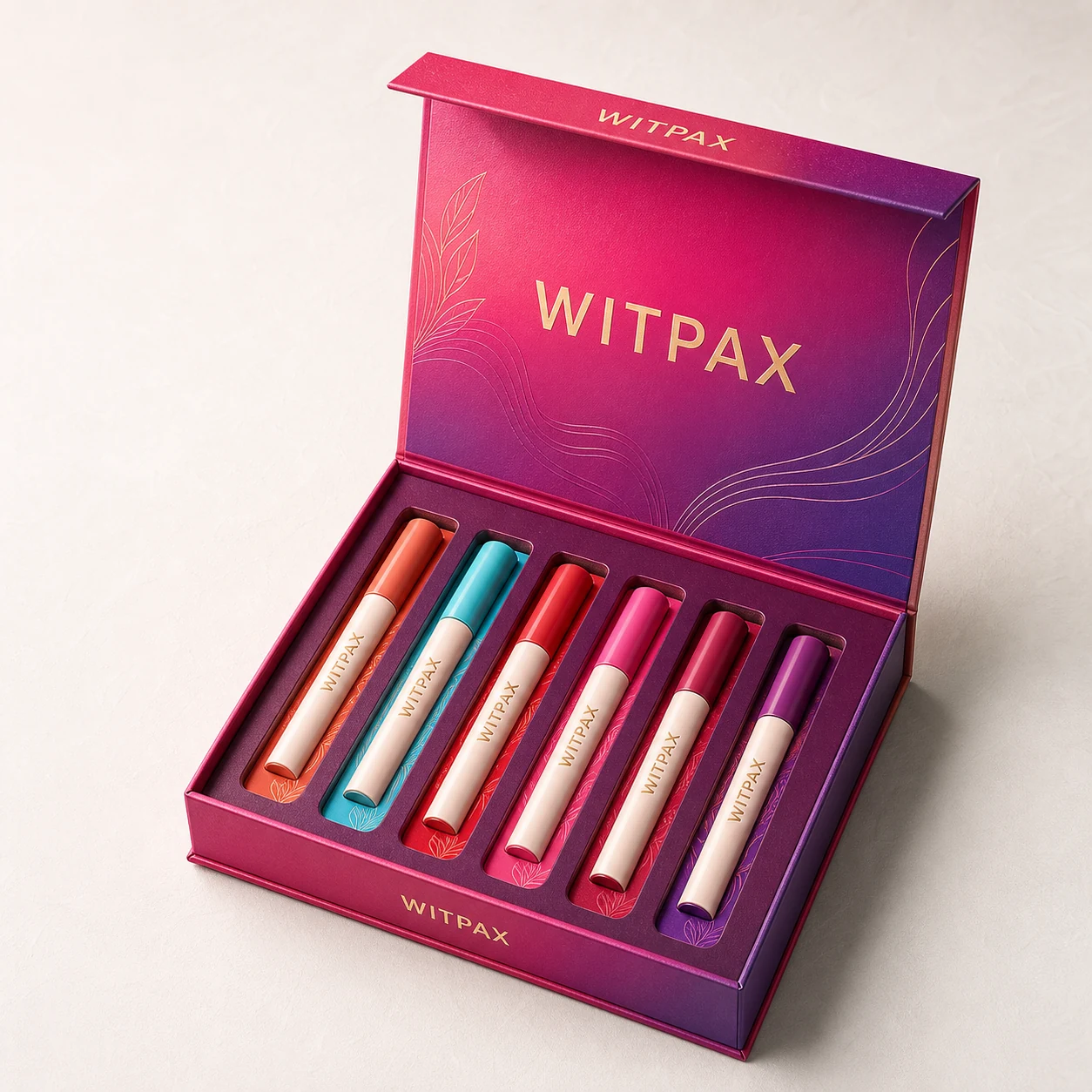 Open magenta WITPAX magnetic cosmetic gift box with six color-coded lip pens secured in fitted insert slots.