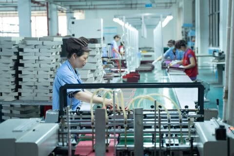 Workers operate machinery in a factory assembly line.