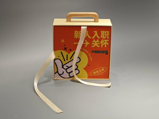 Beige custom packaging box with a detachable orange lid, featuring an artistic design and adjacent loose ribbon