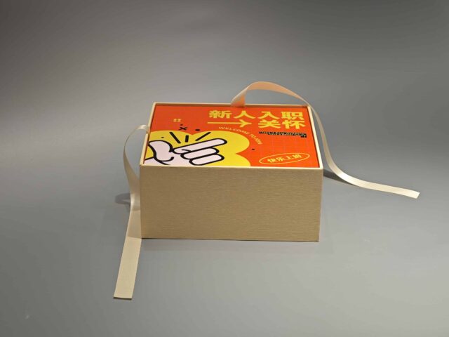 Beige custom packaging box with a detachable orange lid, featuring an artistic design and adjacent loose ribbon