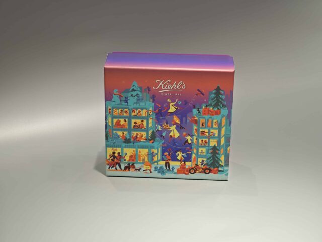 The image showcases a vibrant, customized gift box adorned with lively illustrations of people and animals. It features a unique skincare packaging design, paired with a distinct purple lift-off lid placed nearby.