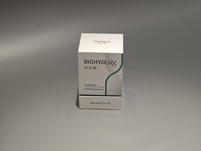 Two custom skincare packaging boxes are stacked on a gray surface, with their lift-off lids slightly ajar. The boxes showcase intricate designs and craftsmanship.