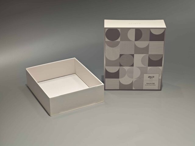 A custom packaging box with a lift-off lid, showcasing an intricate pattern, is displayed elegantly