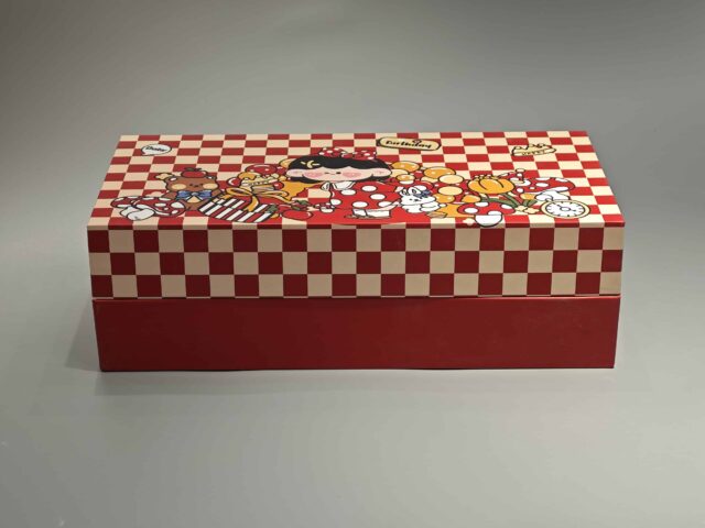 Our product is a custom-designed rectangular gift box in an appealing red color, featuring a checkered lid adorned with playful cartoon characters and food-themed illustrations. This versatile packaging solution is ideal for enhancing any occasion.