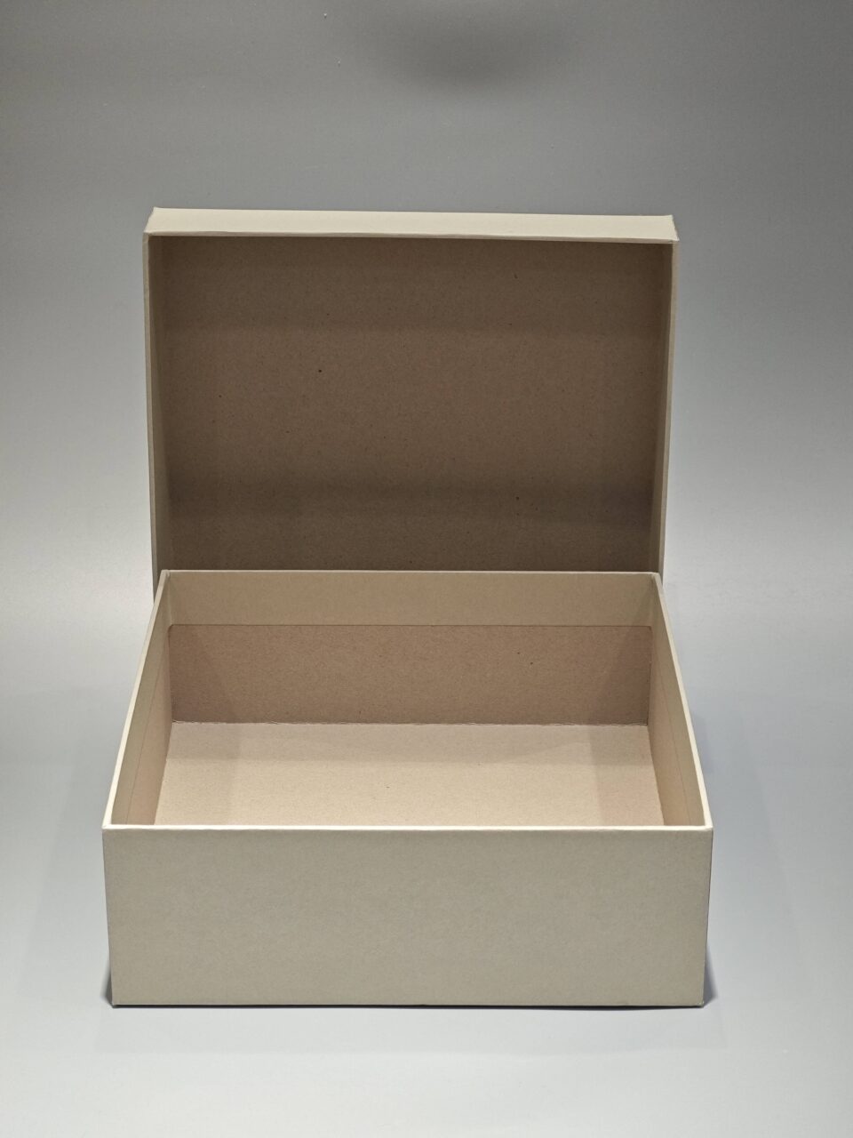 A custom square rigid box with a removable top positioned slightly ajar on the side, set against a neutral backdrop.