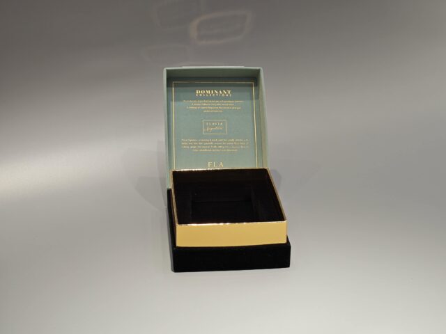 The image showcases two exquisite custom packaging boxes for Flavia perfume. One box features a light green design with silver accents, while the other is dark green with gold accents, both incorporating elegant foil stamping details.