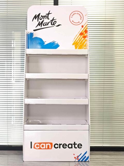 This image shows a custom box packaging design, featuring an empty white display stand. The top features the brand name, and the bottom includes a creative tagline. The display is set against a backdrop of vertical blinds, highlighting its sleek and modern presentation ideal for showcasing products. Instead of actual text on the packaging, think of it as conceptual placeholders that emphasize brand identity and messaging opportunities in product displays.