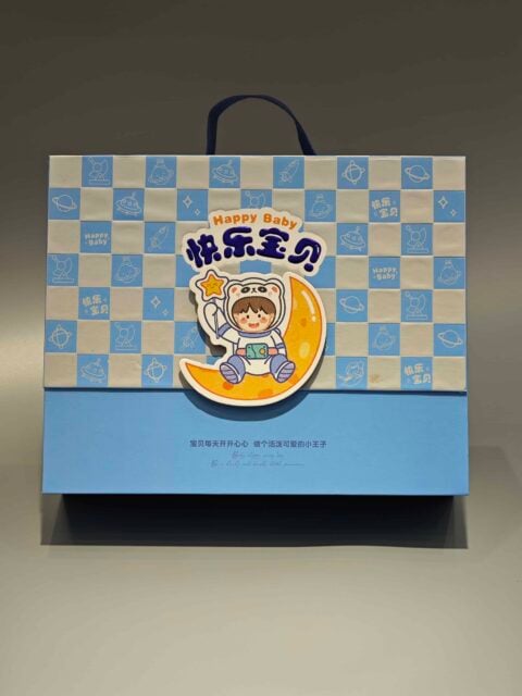 We are a manufacturer of custom box packaging. This product features a design with a child in an astronaut suit sitting on a crescent moon. The box is adorned with checkered blue and white patterns, creating an appealing and whimsical look suitable for celebrating joyful occasions.